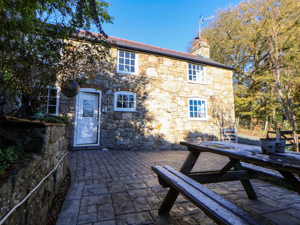 An outdoor area with a stone house and patio furniture at Woodland Cottage in Garth