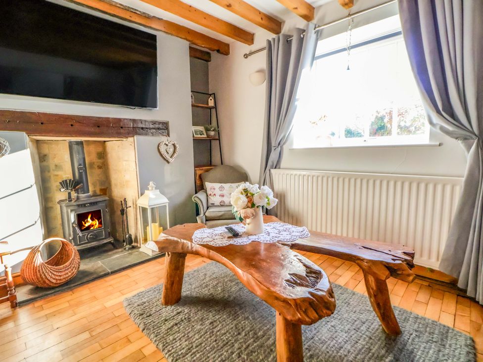A living room with a fireplace and wooden table at Woodland Cottage in Garth