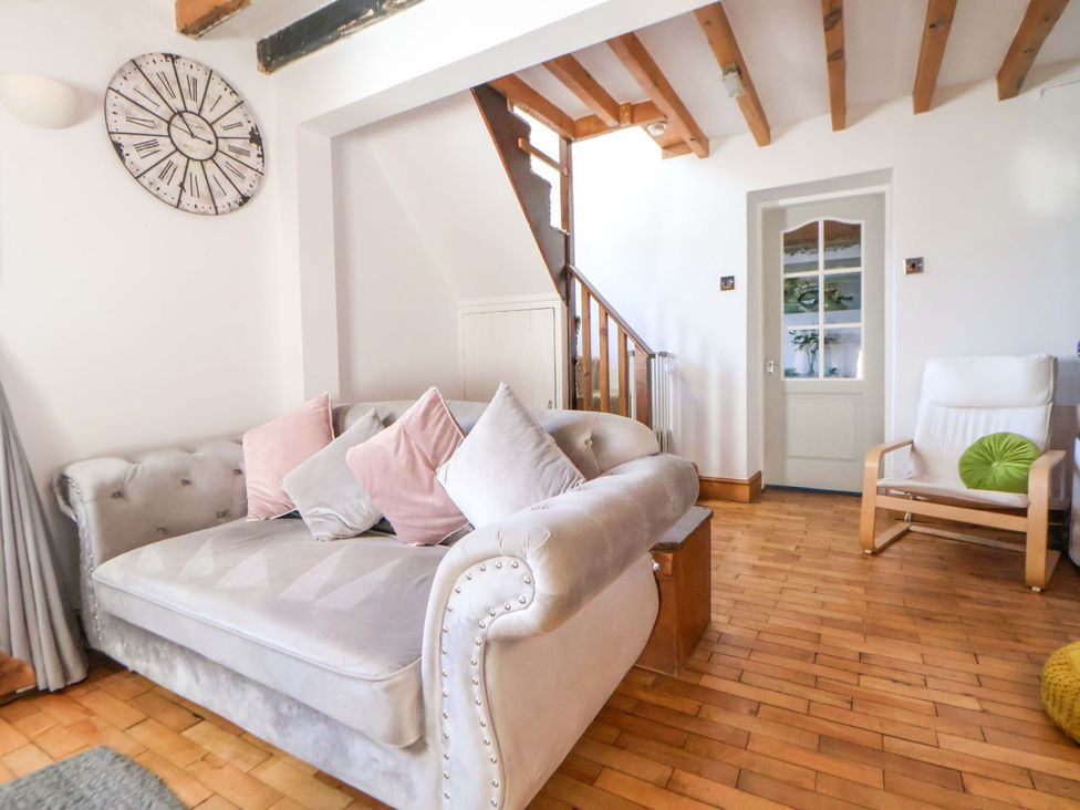 A living room with a sofa and clock at Woodland Cottage in Garth