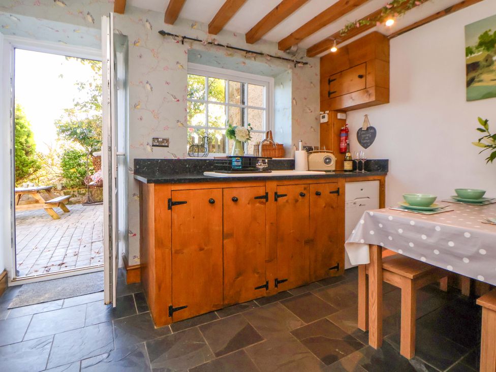 A kitchen with wooden cabinets and a table at Woodland Cottage in Garth