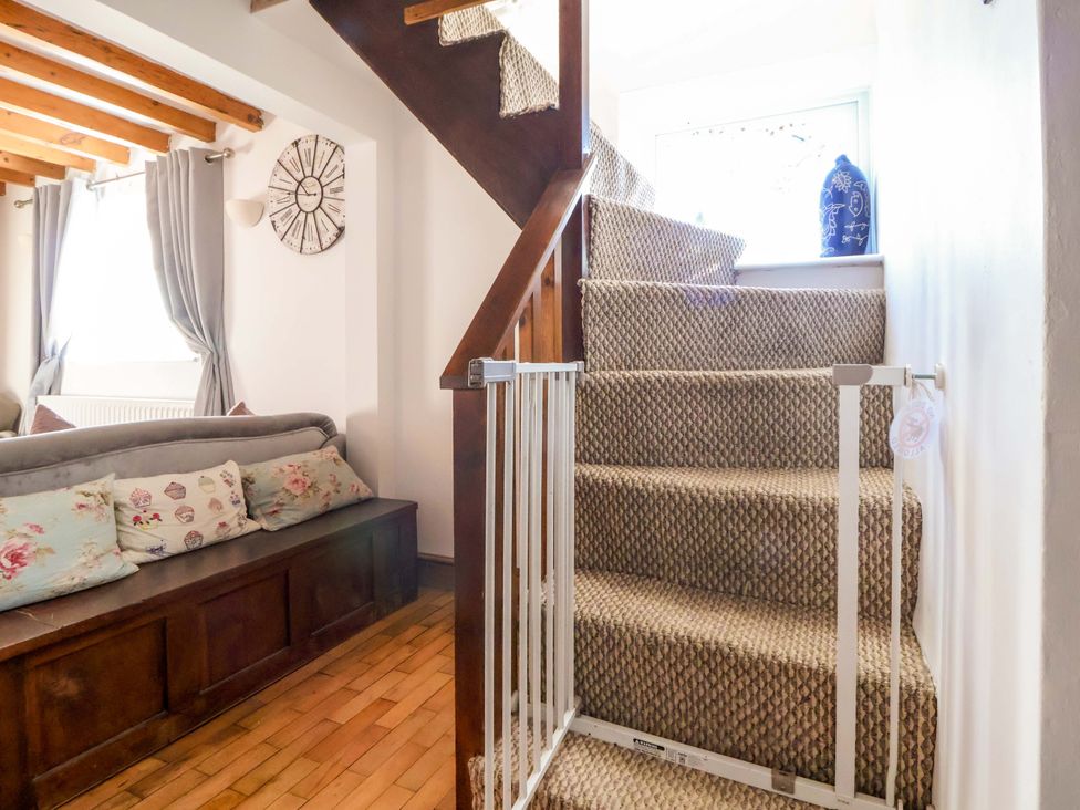 A staircase with a safety gate and a sofa at Woodland Cottage in Garth