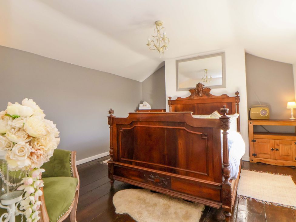 A bedroom with a wooden bed and a flower arrangement at Woodland Cottage in Garth