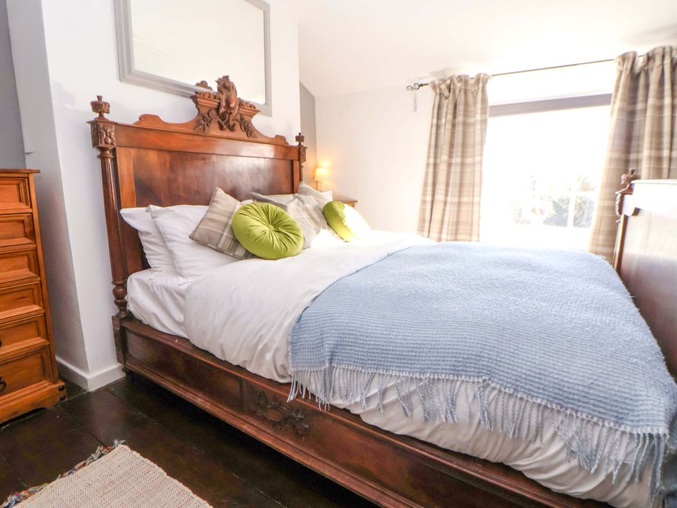 A bedroom with a wooden bed and dresser at Woodland Cottage in Garth
