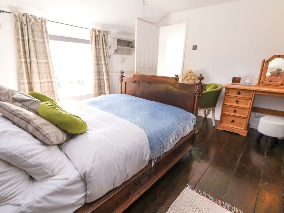 A bedroom with a bed and a chair at Woodland Cottage in Garth