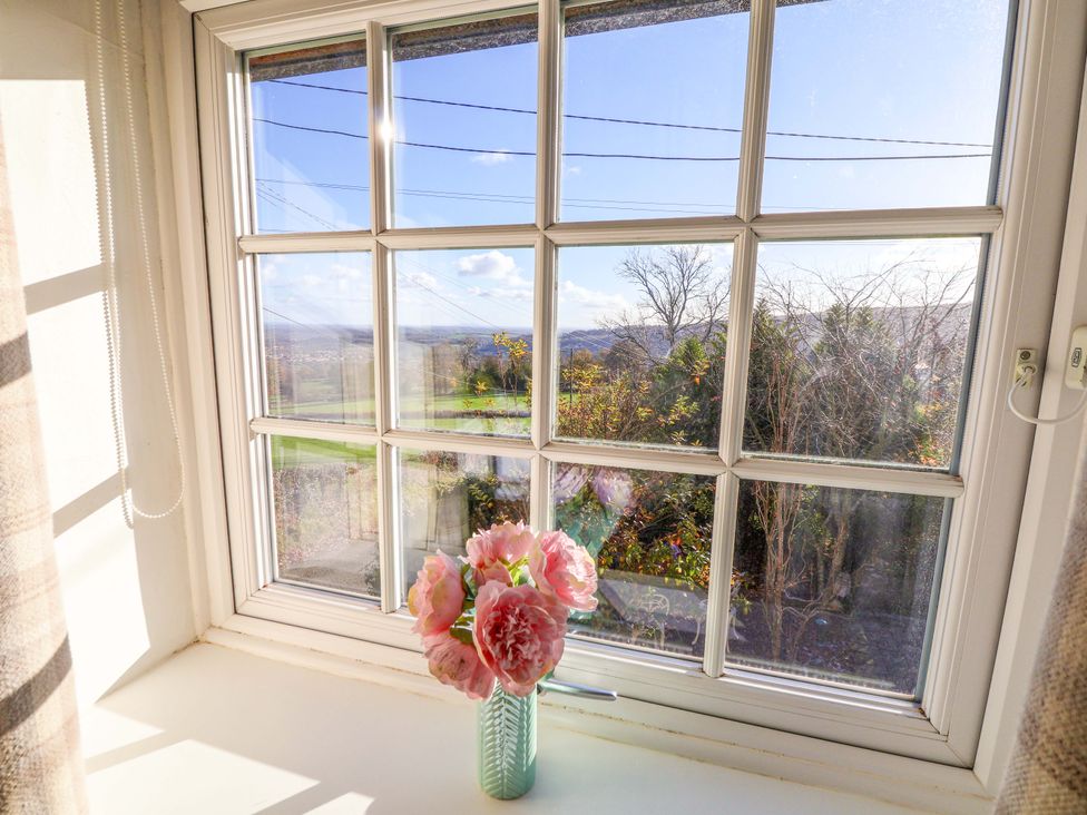 A window with flowers in a vase at Woodland Cottage in Garth