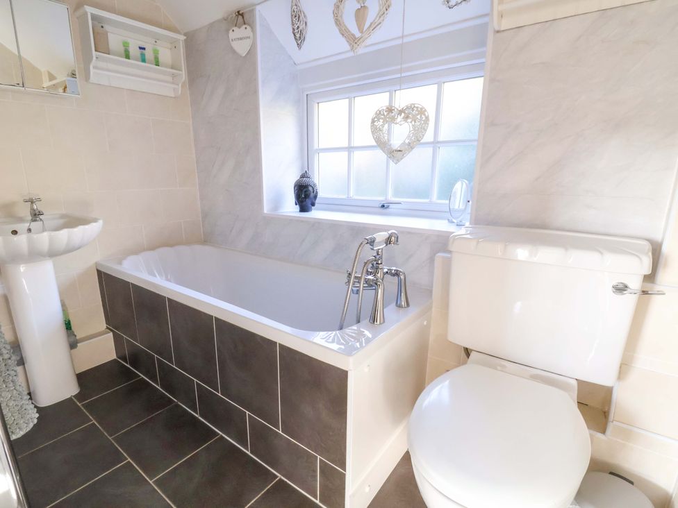 A bathroom with a bathtub, toilet, and sink at Woodland Cottage in Garth