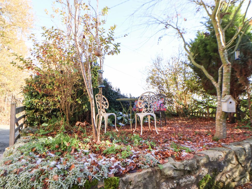A garden with a table and chairs at Woodland Cottage in Garth