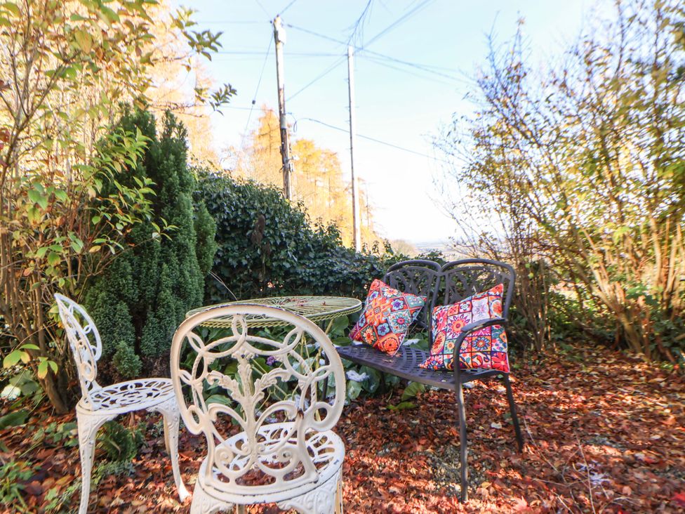 A garden setting with a table and chairs at Woodland Cottage in Garth