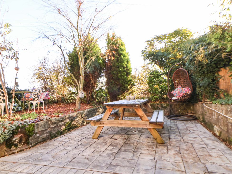 A garden with a picnic table and a hanging chair at Woodland Cottage in Garth