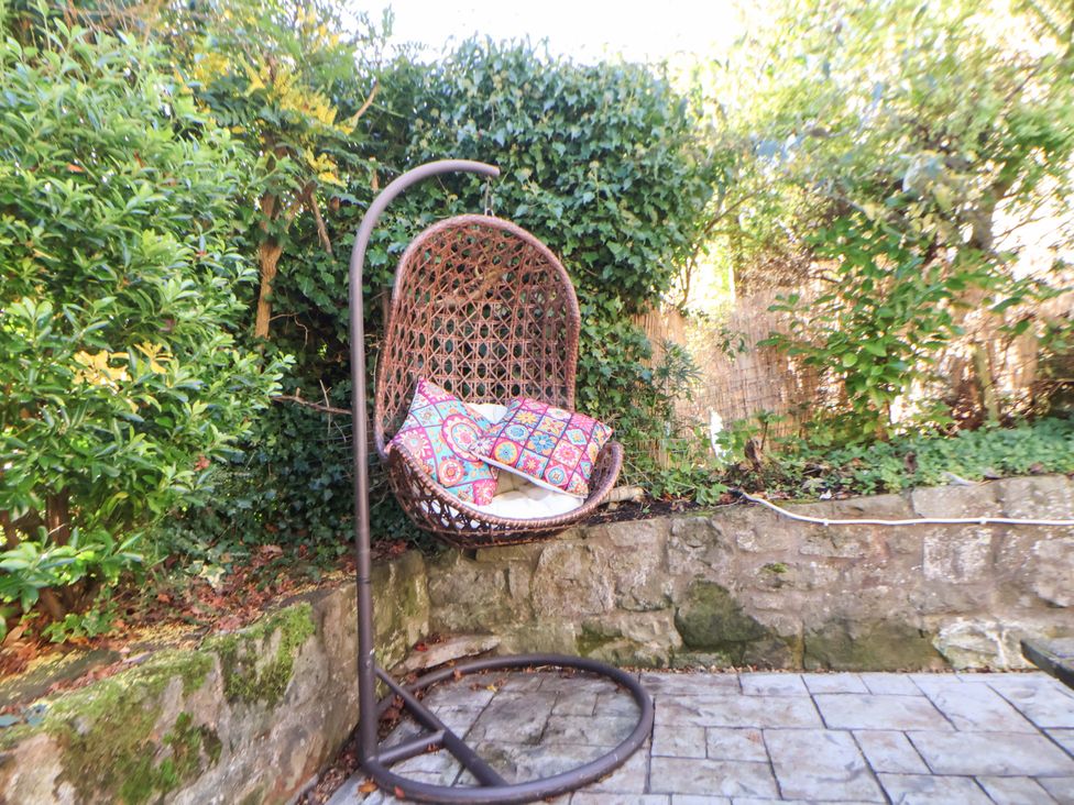 A hanging chair with cushions in an outdoor space at Woodland Cottage in Garth