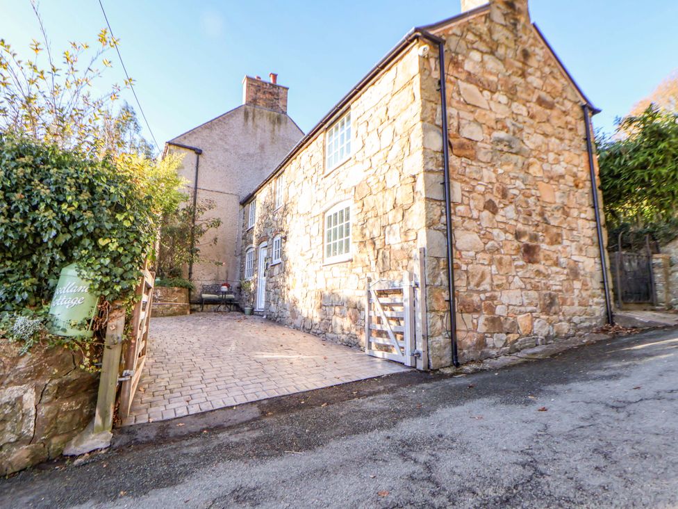 A stone house with a driveway and gate at Woodland Cottage in Garth