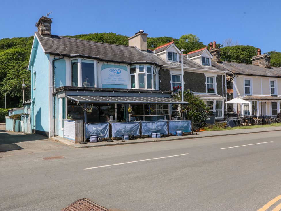 A row of buildings with a cafe called Sea View with outdoor seating on a street at Bay View Apartment in Porthmadog