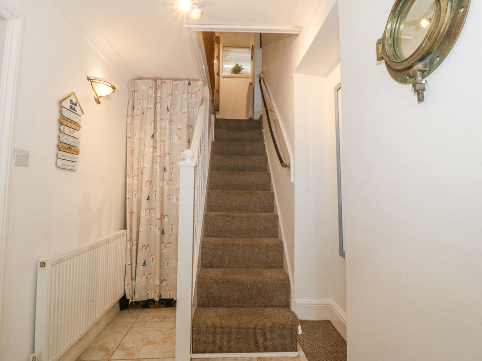 A hallway with carpeted stairs and a radiator next to a curtain at Bay View Apartment in Porthmadog