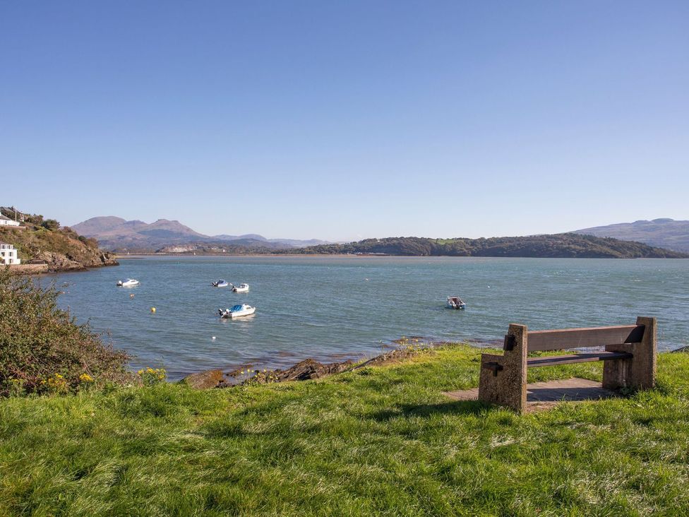 A view of the water with boats and a bench at Bay View Apartment in Porthmadog