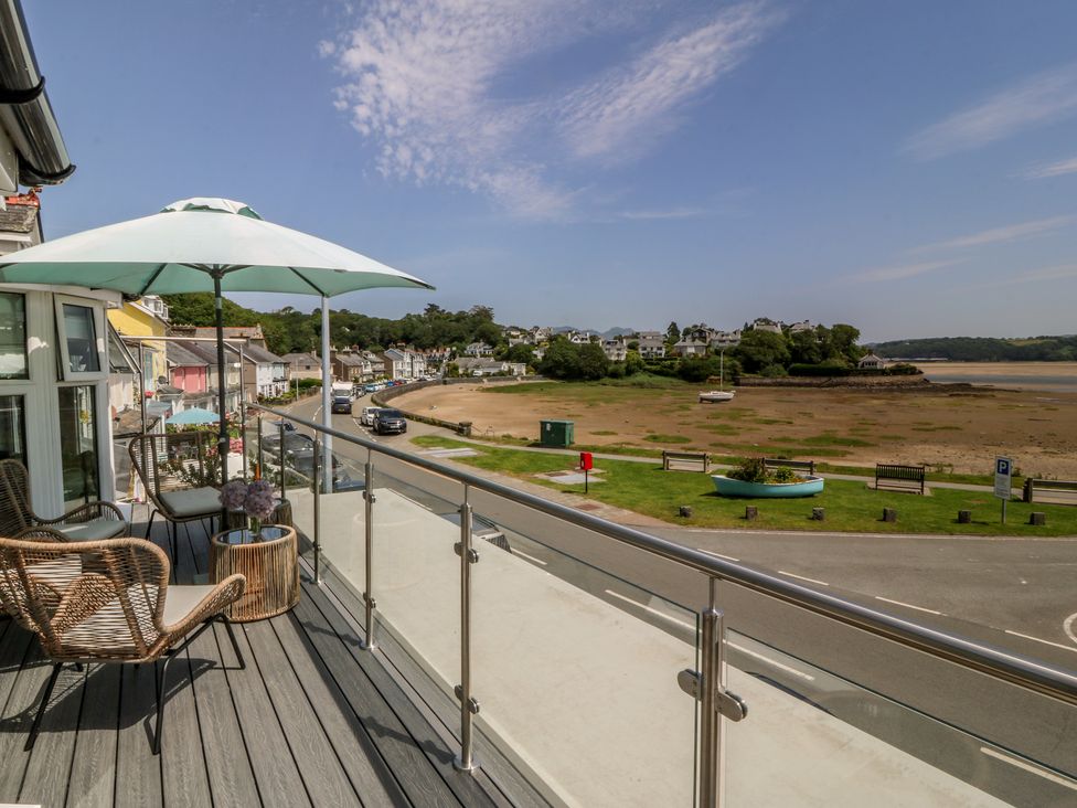 A balcony with chairs and an umbrella overlooking a view at Bay View Apartment in Porthmadog