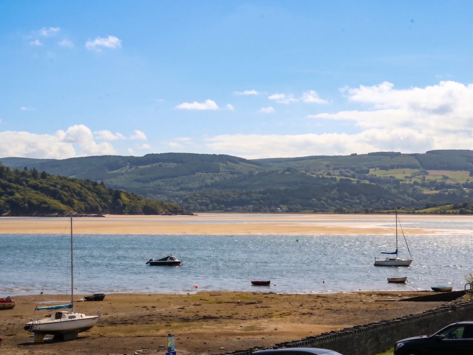 A view of boats on water with mountains in the background at Bay View Apartment Porthmadog