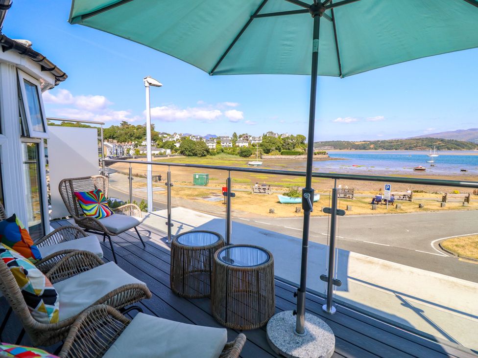 A balcony with chairs and table overlooking water at Bay View Apartment in Porthmadog