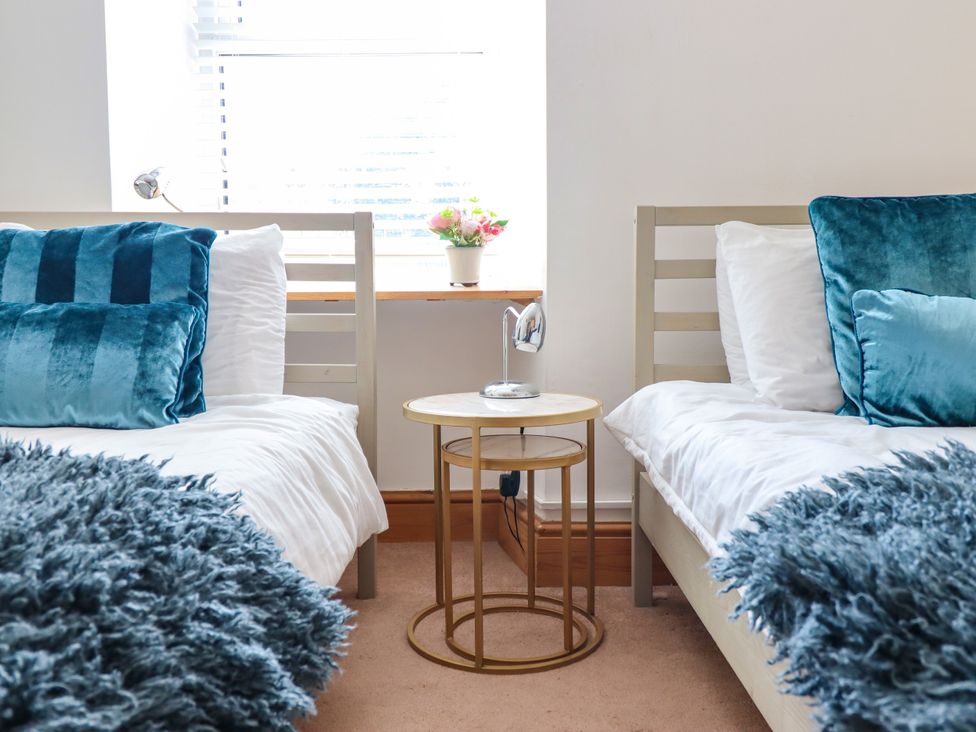 A bedroom with two beds and a side table at Bay View Apartment in Porthmadog