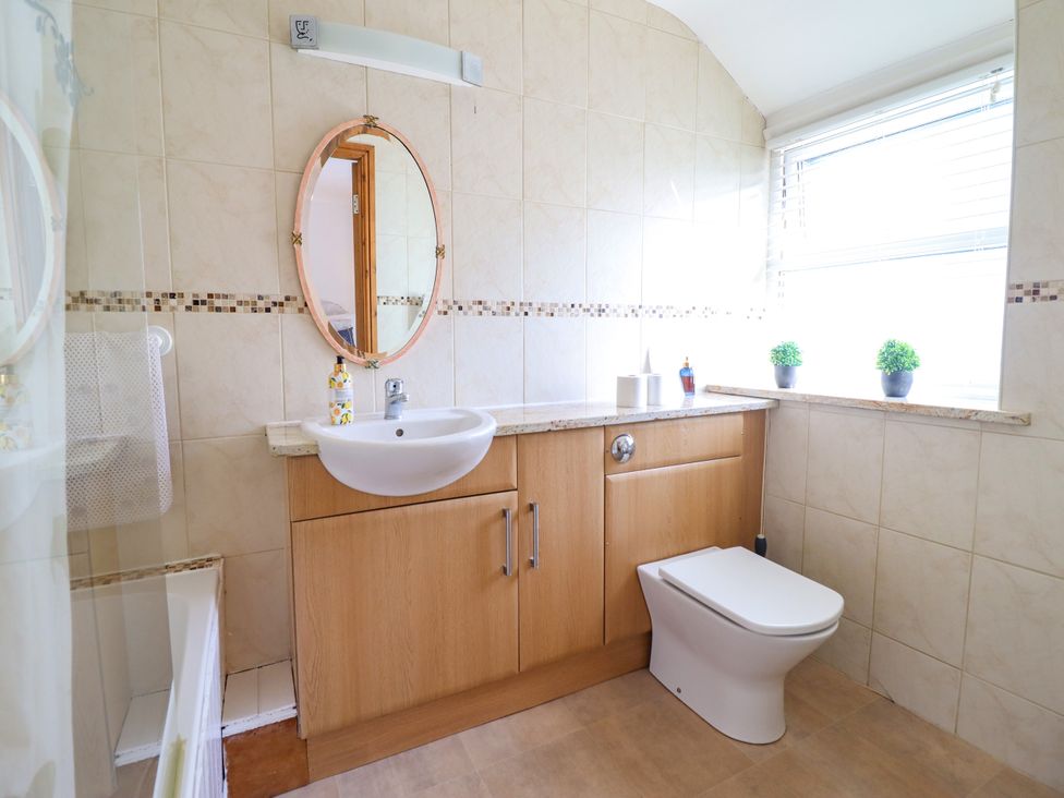 A bathroom with a sink, mirror, and toilet at Bay View Apartment in Porthmadog