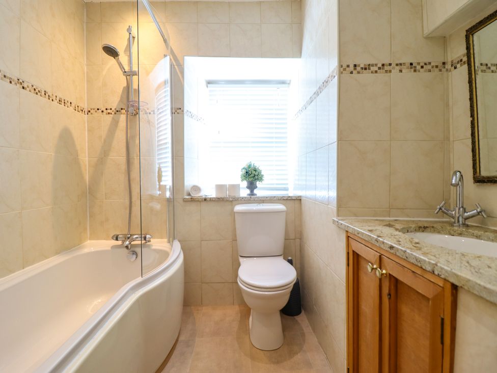 A bathroom with a bathtub, shower, toilet, and sink at Bay View Apartment in Porthmadog