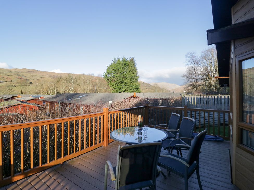 A deck with a table and chairs overlooking hills at Heights View