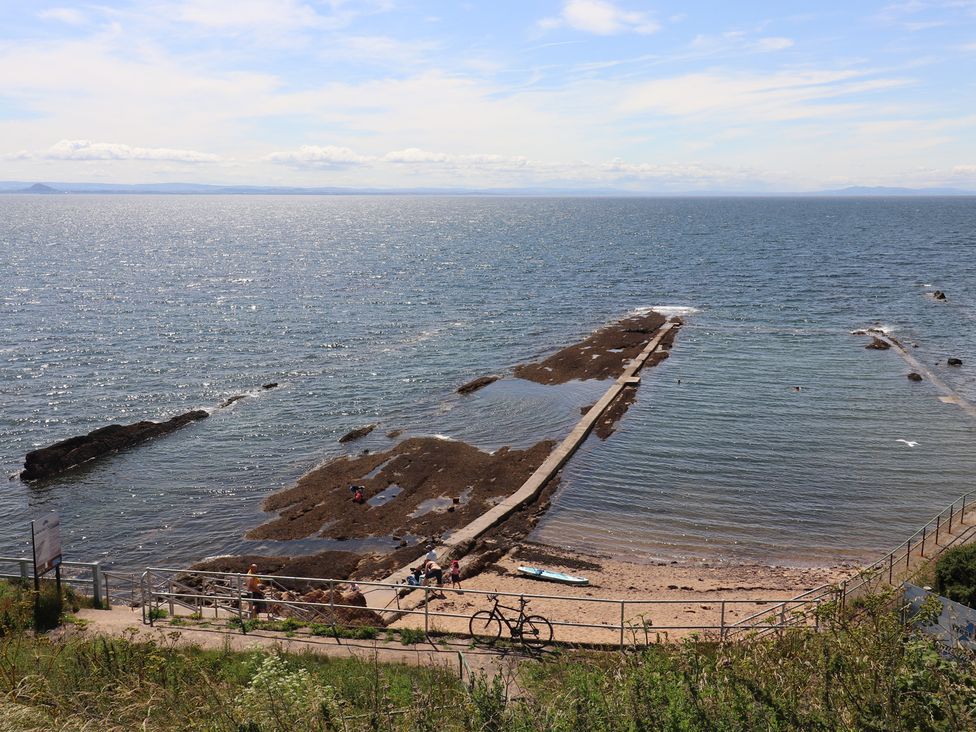A rocky shoreline with a path and bicycle near the ocean at Maimie’s Harbourview Pittenweem near Anstruther
