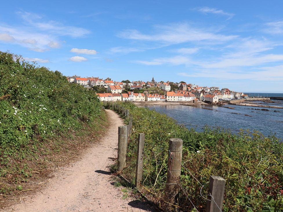A coastal view with a path, fence, and houses at Maimie’s Harbourview in Pittenweem near Anstruther