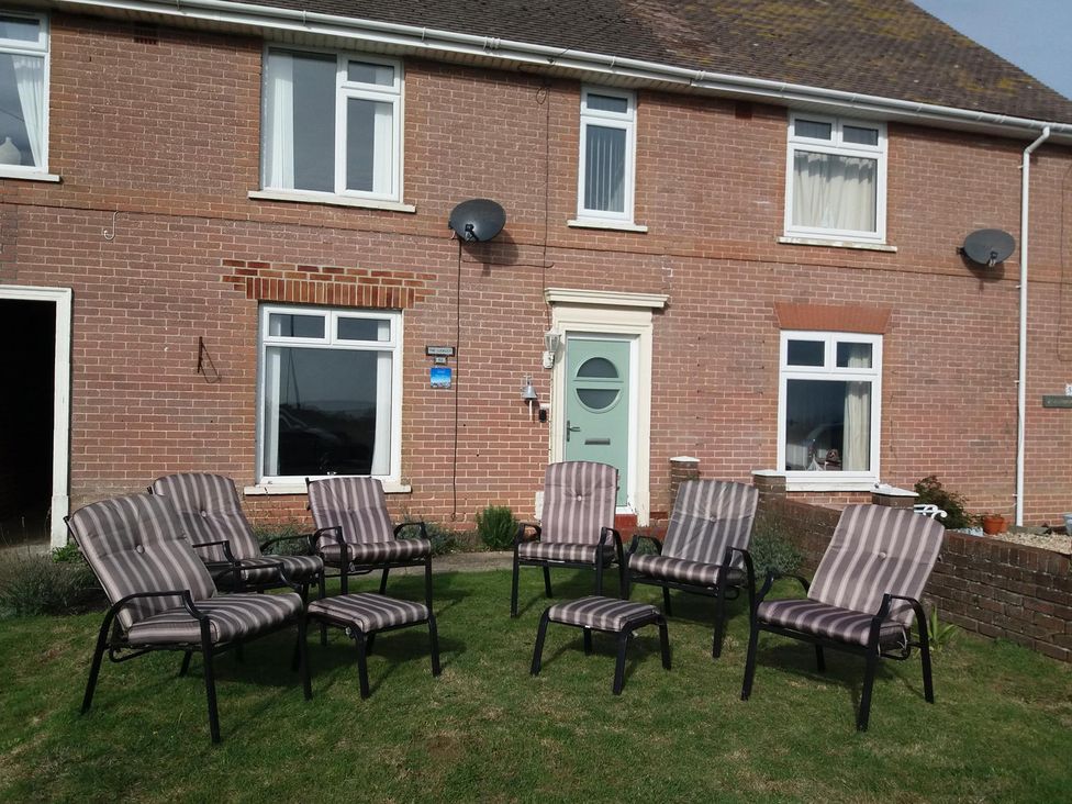 A garden with chairs in front of a brick house at The Lookout -The House With A View Weymouth