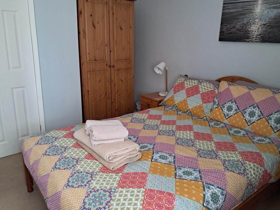 A bedroom with a bed and towels arranged at The Lookout -The House With A View in Weymouth
