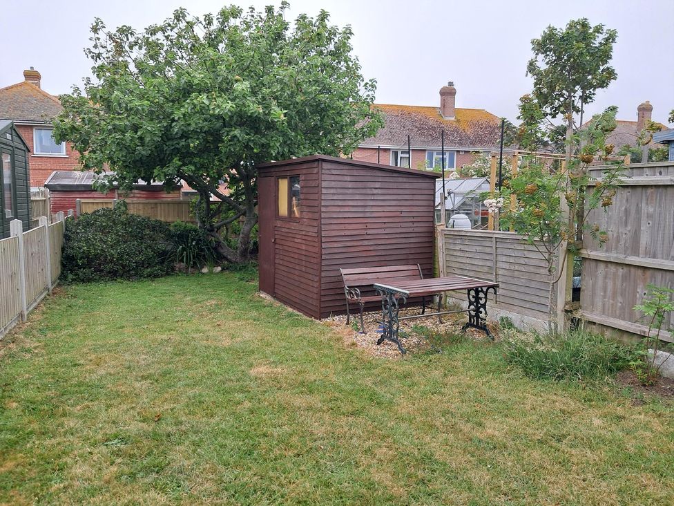 A garden with a shed and table set at The Lookout -The House With A View in Weymouth