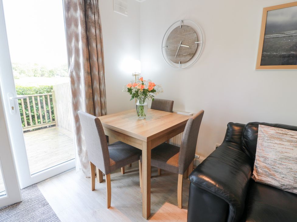 A dining table with chairs and a flower vase at Simply Suite in Castle Douglas