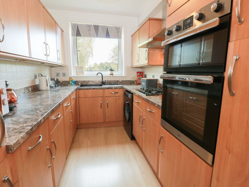 A kitchen with cabinets, sink, and oven at Simply Suite in Castle Douglas