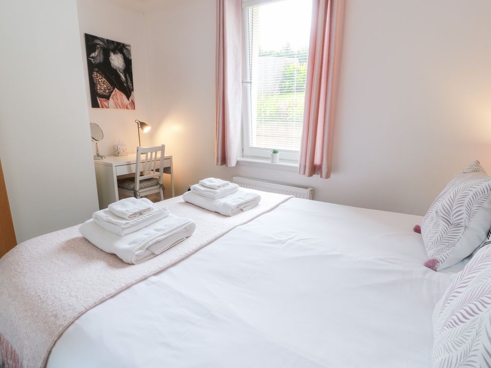 A bedroom with towels on a bed and a desk with a chair at Simply Suite in Castle Douglas