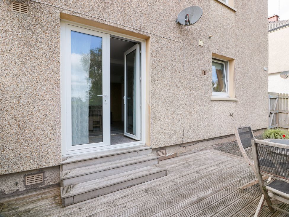 An outdoor area with double doors and a wooden deck at Simply Suite Castle Douglas