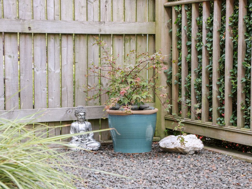 A garden area with a Buddha statue and a flower pot at Simply Suite, Castle Douglas