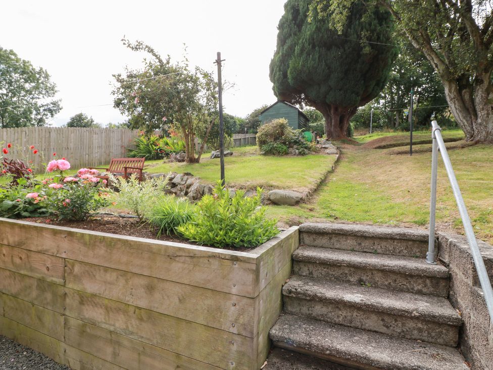 A garden with flowers and a bench at Simply Suite in Castle Douglas