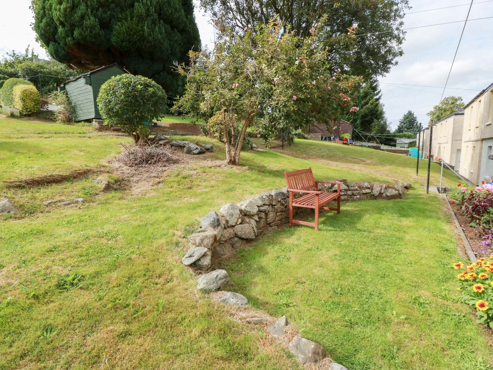 A garden with a bench and stone wall at Simply Suite, Castle Douglas
