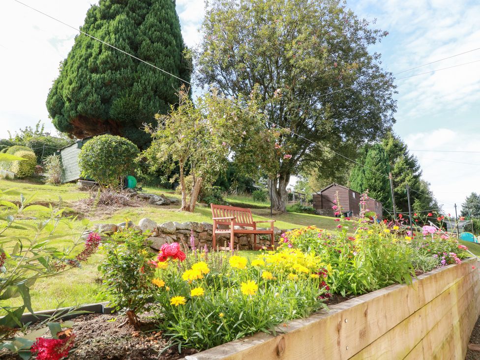 A garden with flowers and a bench at Simply Suite in Castle Douglas
