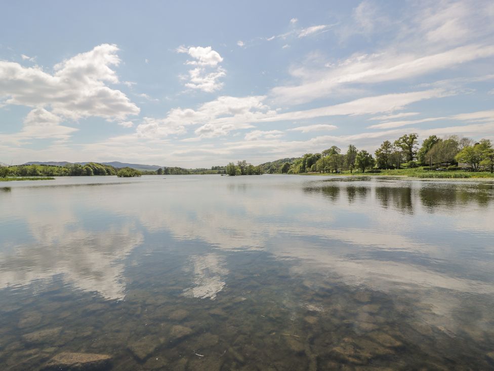 A lake with trees and mountains in the background at Simply Suite in Castle Douglas