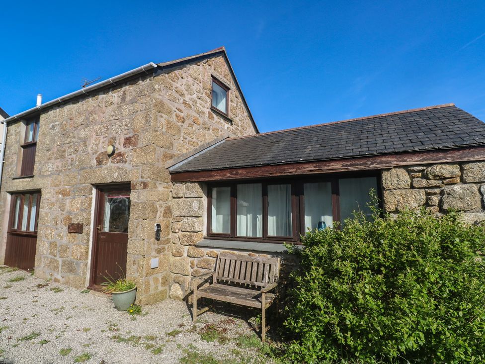 An exterior view of a stone building with a bench at Kernyk in Penzance