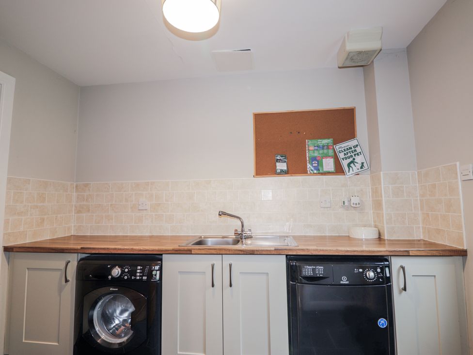 A kitchen with washing machine, sink, and dishwasher at Burnside House in Aviemore