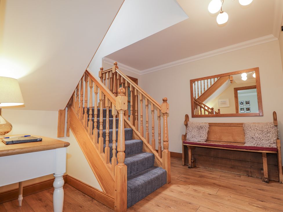 A hallway with a staircase and a bench at Burnside House in Aviemore