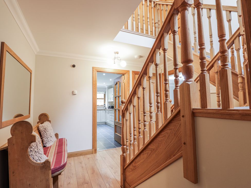 A hallway with a staircase and bench at Burnside House Aviemore
