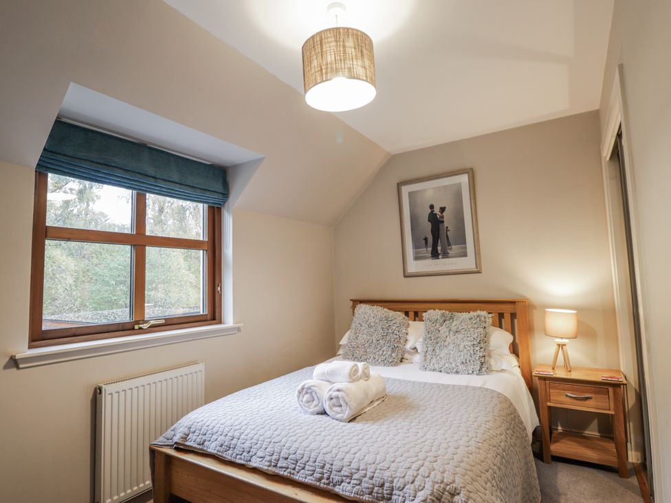 A bedroom with a bed and window at Burnside House in Aviemore