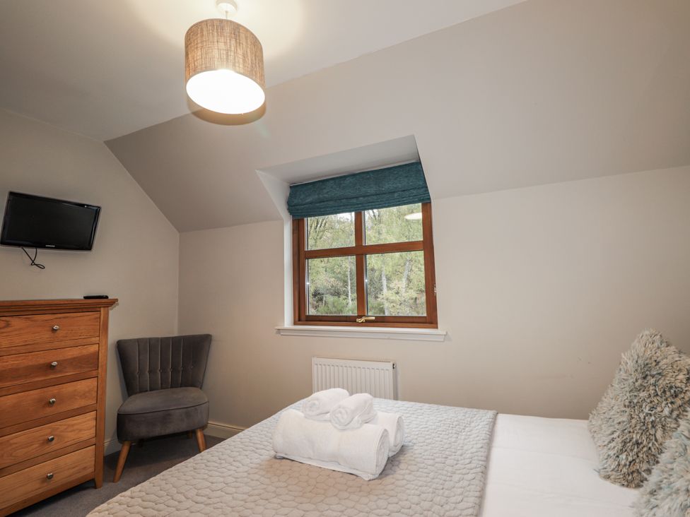 A bedroom with a bed, chest of drawers, and television at Burnside House in Aviemore