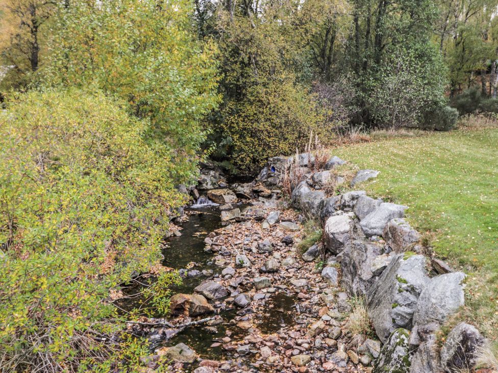 A stream surrounded by rocks and vegetation at Burnside House in Aviemore
