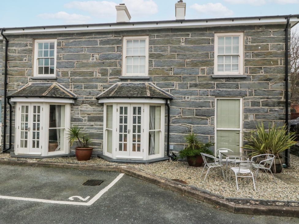 An outdoor area with stone wall and seating at Bwthyn Llechen in Porthmadog