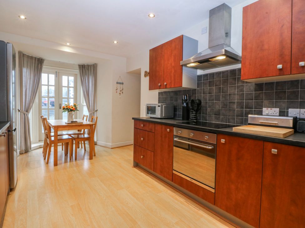 A kitchen with cabinets and a dining table at Bwthyn Llechen in Porthmadog