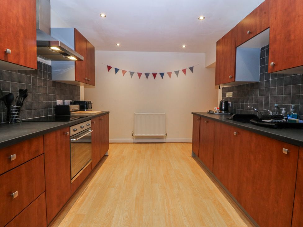 A kitchen with wooden cabinets and appliances at Bwthyn Llechen in Porthmadog