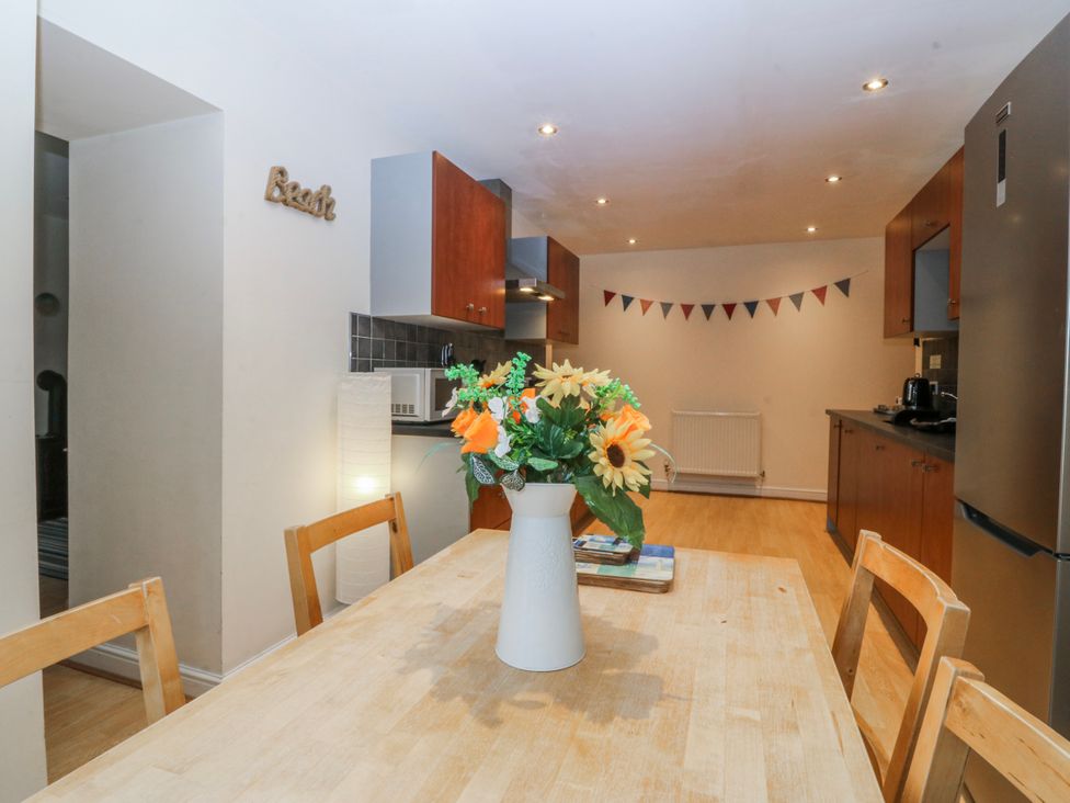 A kitchen with a dining table and flower vase at Bwthyn Llechen in Porthmadog